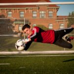 Goalie catching soccer ball with sports photography