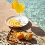 lifestyle photography for property management vacation rentals Living Essaouira showing fresh squeezed orange juice and sunglasses sitting beside crystal clean turquoise pool
