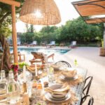 Photography and photo styling for Living Essaouira property management group in Essaouira Morocco. Elegantly table setting with lounge chairs setting sun and pool in the background.